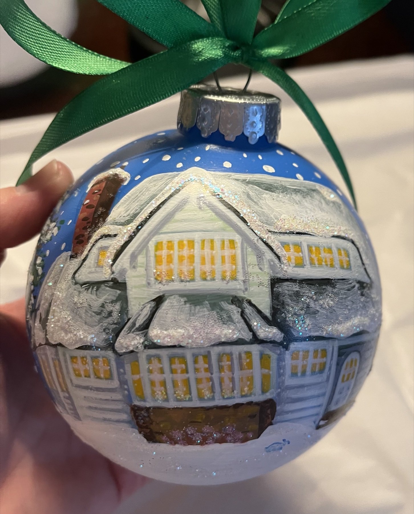 Blue glass ornament painted with a snow-covered Cleveland house
