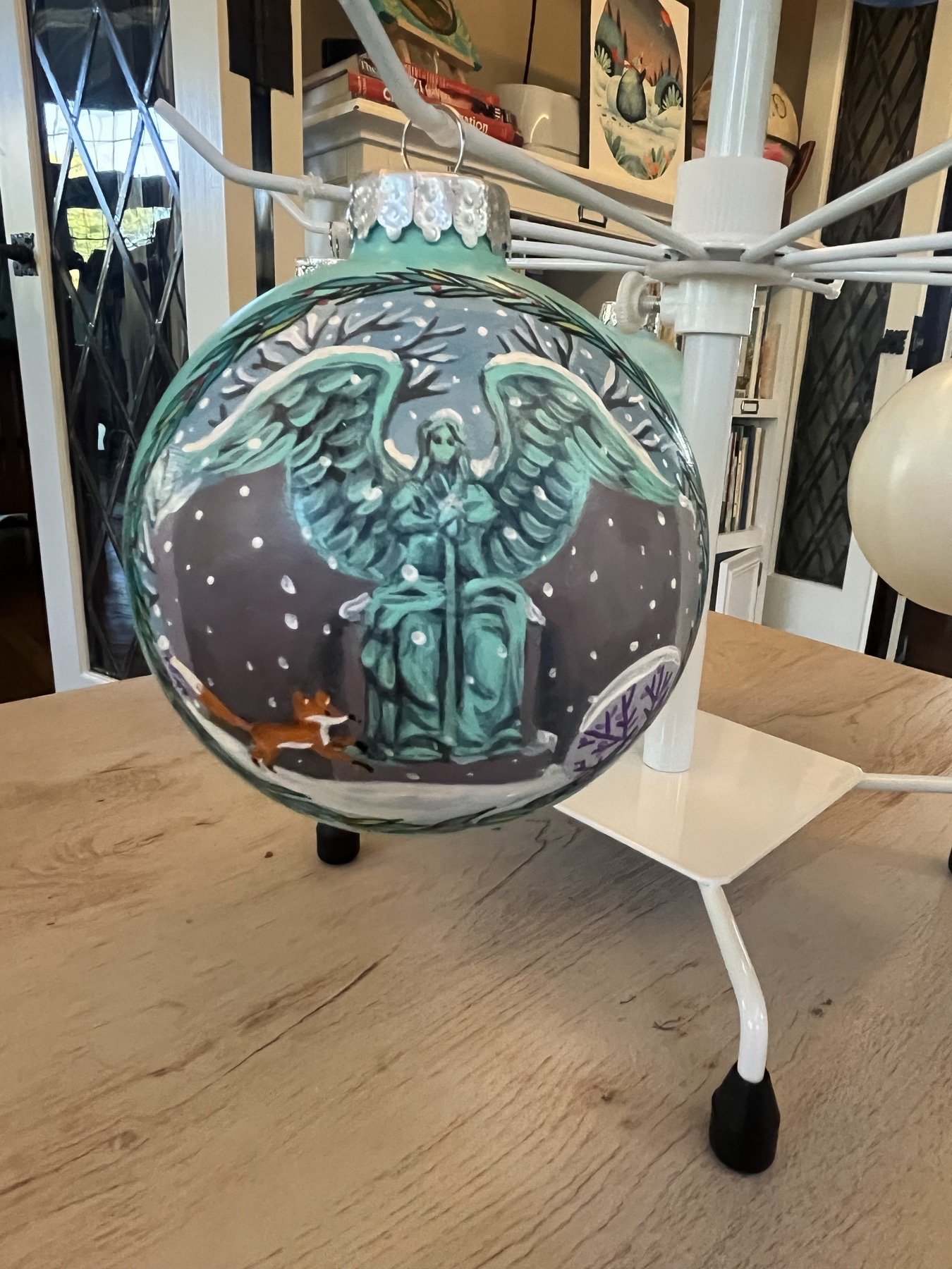 Dark glass ornament painted with a woodland animal beneath branches and stars